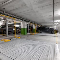Flere biler står parkert på parkeringsplattformen i en parkeringskjeller.