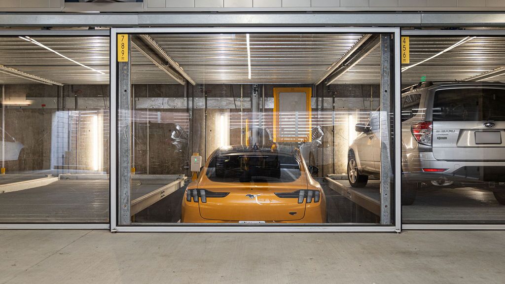 Bildet viser en gul sportsbil i et parkeringssystem inne i en moderne parkeringskjeller.