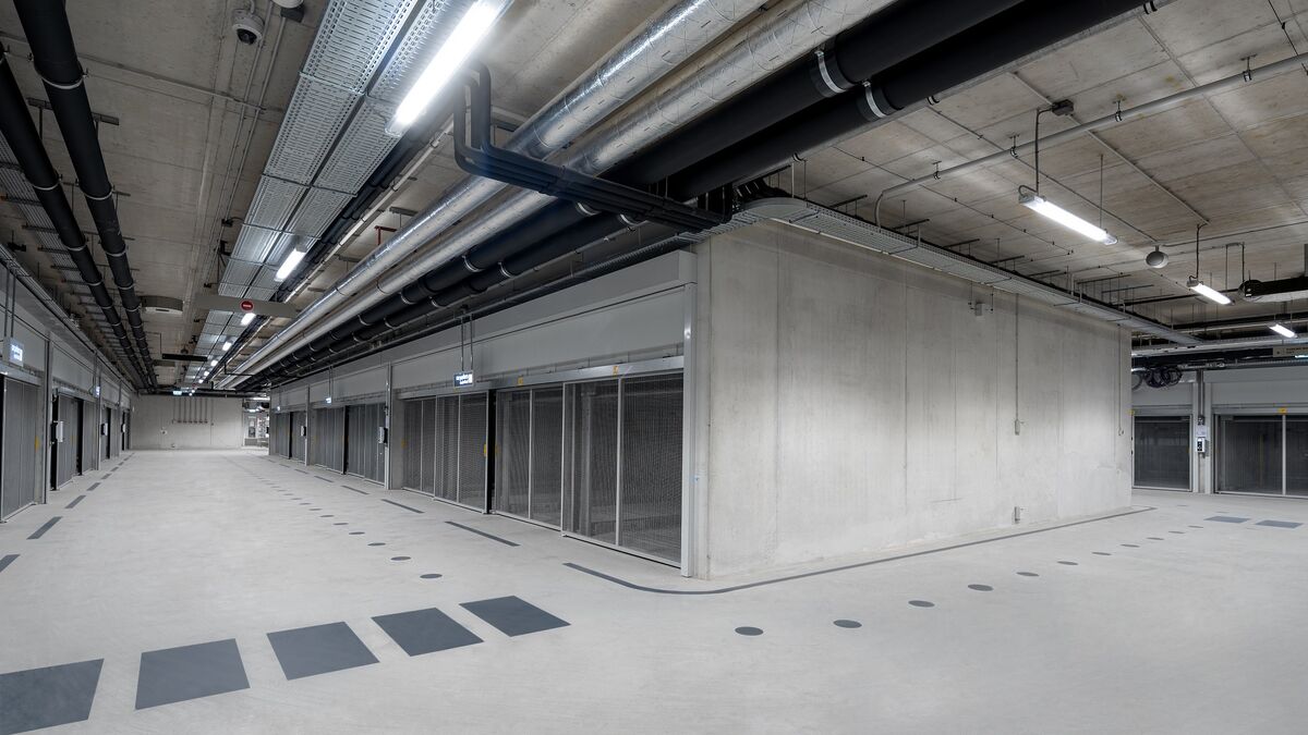 Moderne parkeringskjeller med kryssområde, gjennomgående kjørefelt og parkeringssystemer på begge sider.