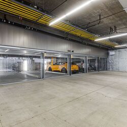 Bildet viser en moderne parkeringskjeller med flere innglassede parkeringsplasser i et parkeringssystem.