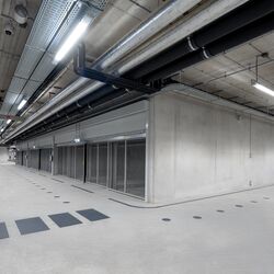 Moderne parkeringskjeller med kryssområde, gjennomgående kjørefelt og parkeringssystemer på begge sider.