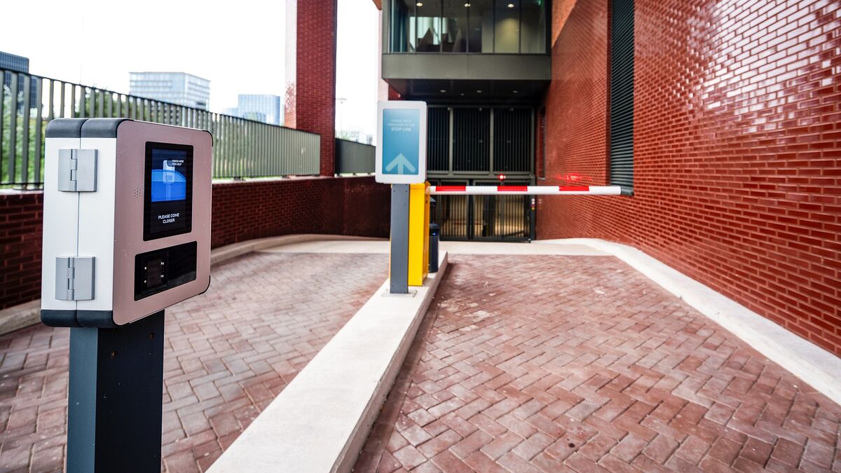 Innkjøring til et moderne parkeringssystem med adgangsterminal, digitalt veiledningssystem og automatisk bom.