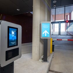 Utkjøring fra et moderne parkeringssystem med adgangsterminal, digitalt førerinformasjonssystem og automatisk bom.